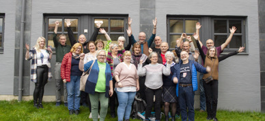 Fylkessekretærene og fylkeslederne i Norsk Bonde- og Småbrukarlag står ute foran en grå vegg og jubler med hendene i været. De smiler. Bildet er tatt under landsmøtet i 2021. - Foto: Nora May Engeseth/NBS