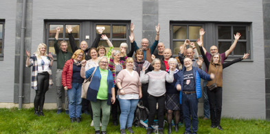 Fylkessekretærene og fylkeslederne i Norsk Bonde- og Småbrukarlag står ute foran en grå vegg og jubler med hendene i været. De smiler. Bildet er tatt under landsmøtet i 2021. - Foto: Nora May Engeseth/NBS